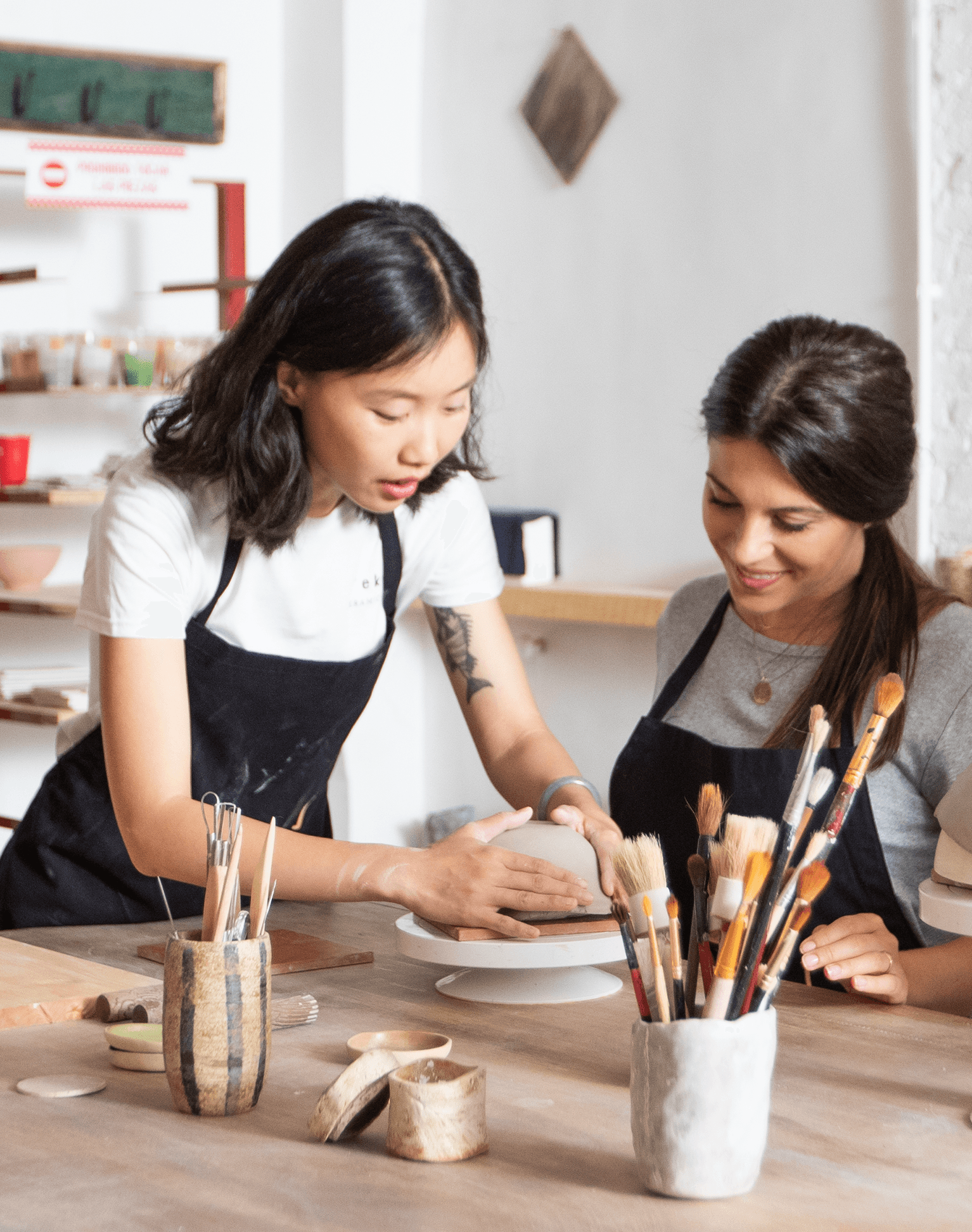 Two ceramicists working on a bowl in a ceramics studio.